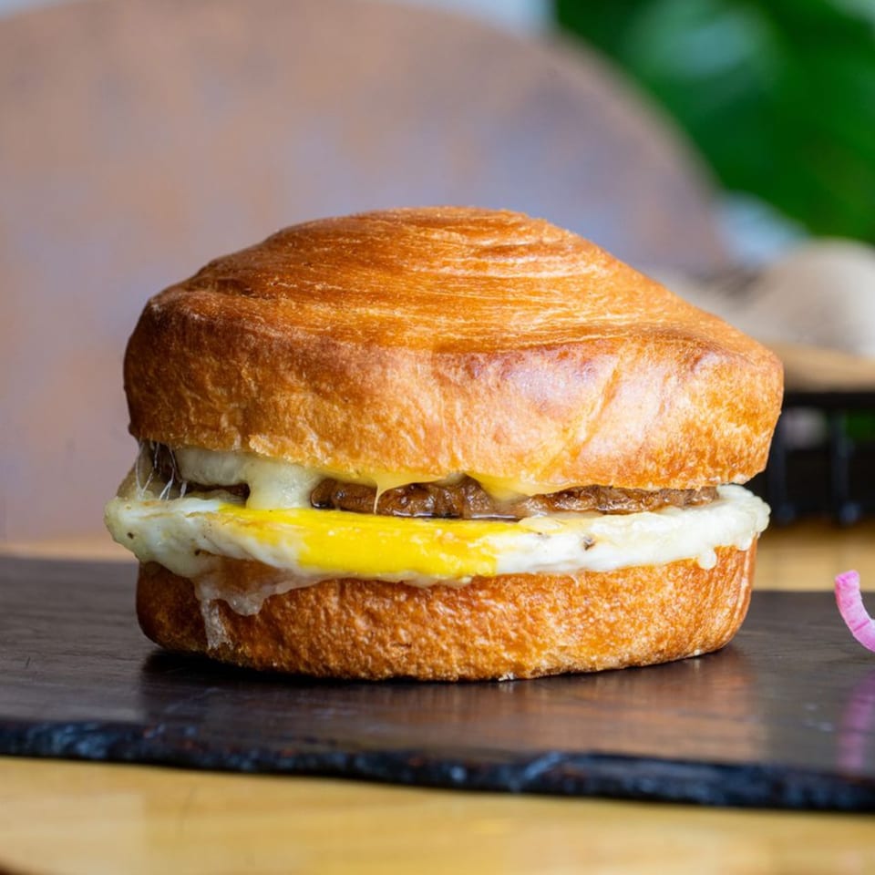 A Cafe COPA breakfast sandwich with egg, cheese, and sausage on a golden croissant.